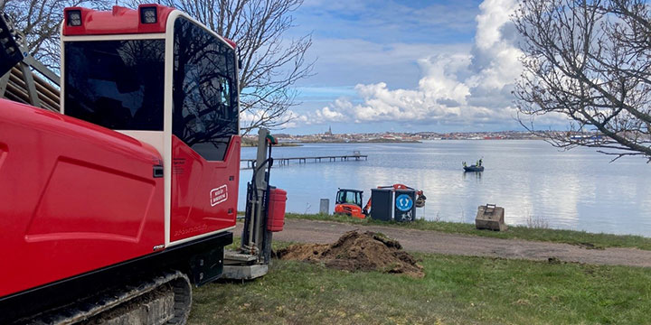 ett rött arbetsfordon ståendes på stranden i Bökevik. I bakgrunden syns havet och sanden